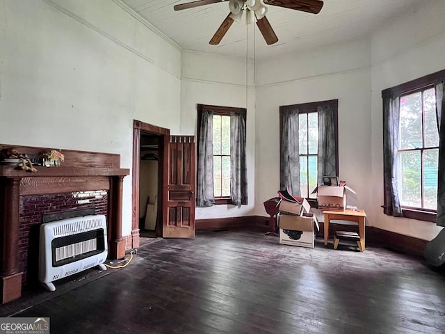 living room with heating unit, dark hardwood / wood-style floors, ceiling fan, and a wealth of natural light