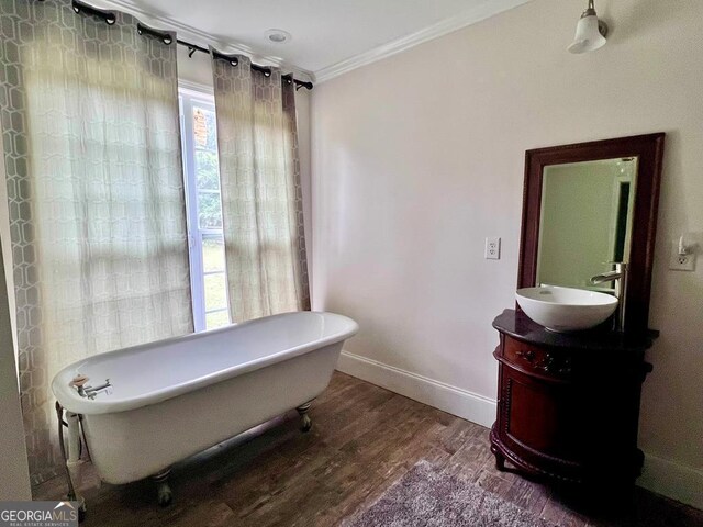 bathroom featuring a tub to relax in, wood-type flooring, vanity, and ornamental molding