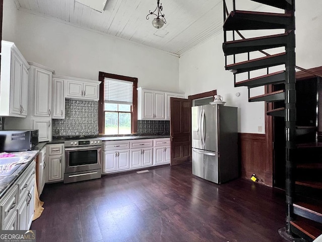 kitchen featuring appliances with stainless steel finishes, dark hardwood / wood-style flooring, white cabinets, and backsplash