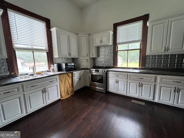 kitchen featuring a healthy amount of sunlight, white cabinetry, tasteful backsplash, and stainless steel stove