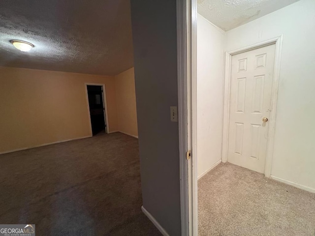 hallway with carpet flooring and a textured ceiling