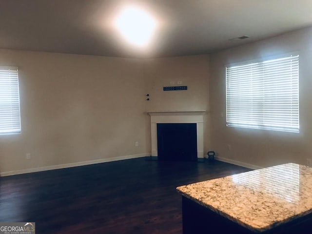 unfurnished living room with dark wood-type flooring, a fireplace, and baseboards