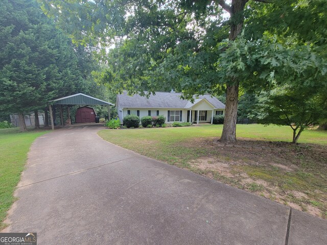 ranch-style home with a carport, a front lawn, and an outdoor structure