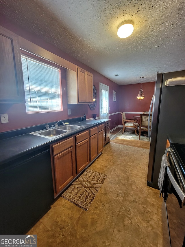 kitchen with sink, a textured ceiling, range, and pendant lighting