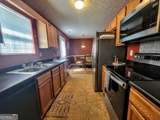 kitchen featuring a textured ceiling, hanging light fixtures, light tile patterned floors, stainless steel appliances, and sink