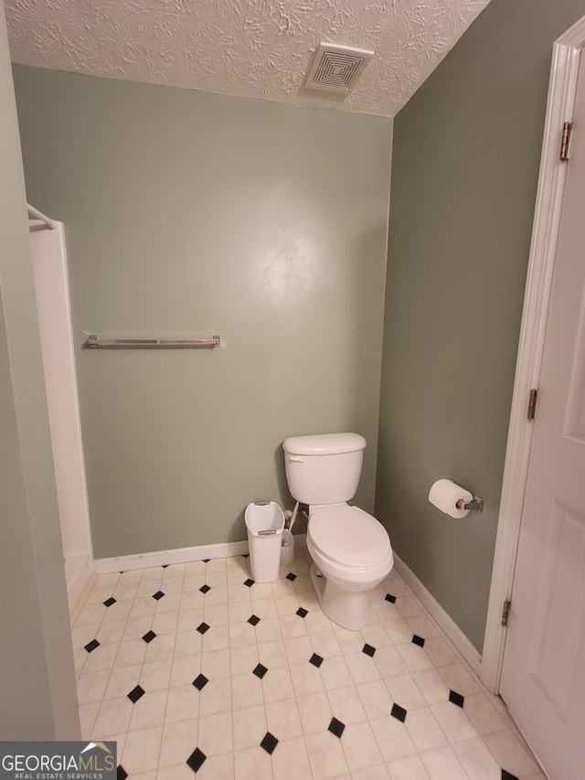 bathroom with tile patterned floors, a textured ceiling, and toilet