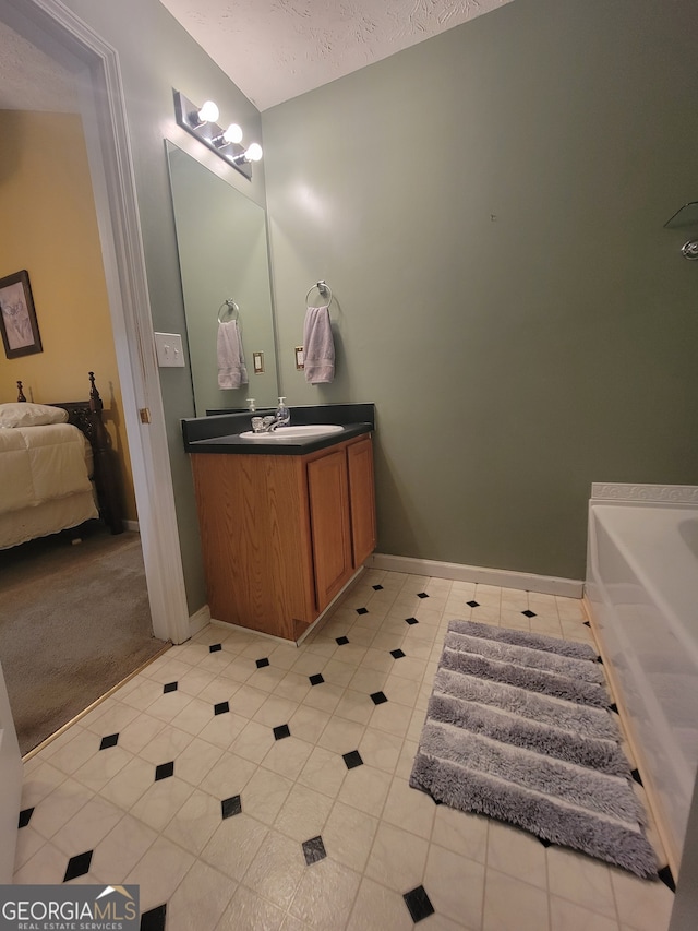 bathroom with a bathing tub, vanity, and tile patterned flooring