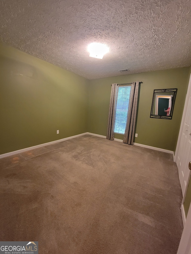 carpeted spare room with a textured ceiling