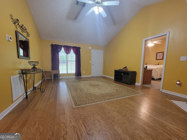 unfurnished living room featuring ceiling fan, lofted ceiling, a textured ceiling, and hardwood / wood-style floors