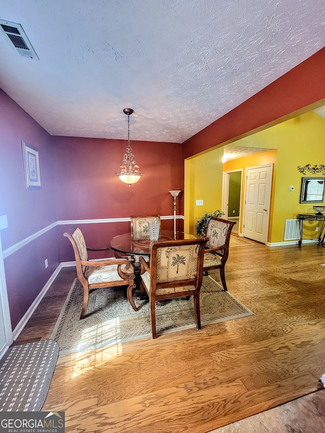 dining room with a textured ceiling and light wood-type flooring