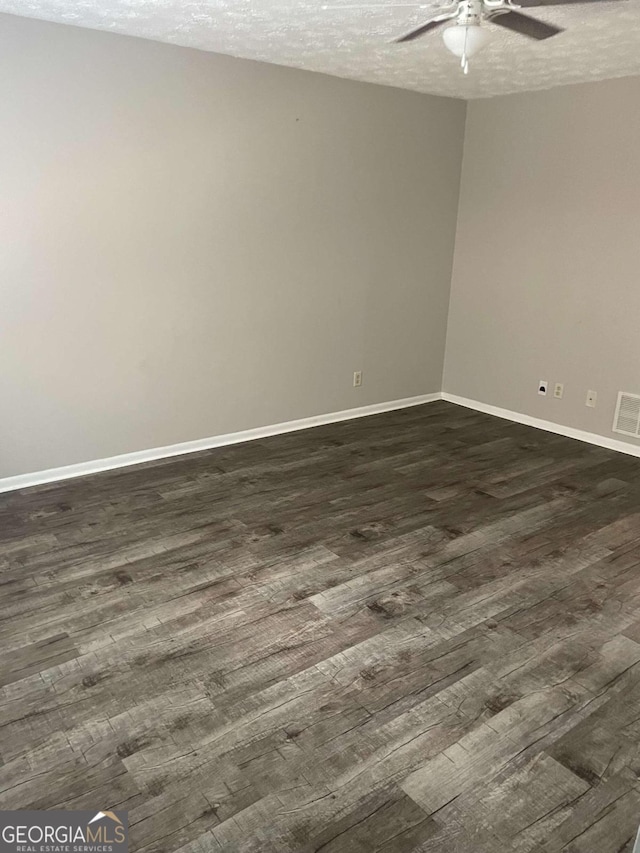 unfurnished room with a textured ceiling, dark wood-type flooring, and ceiling fan