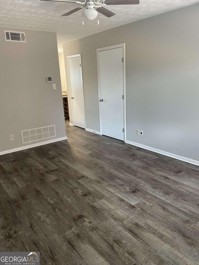 unfurnished room with ceiling fan, dark wood-type flooring, and a textured ceiling