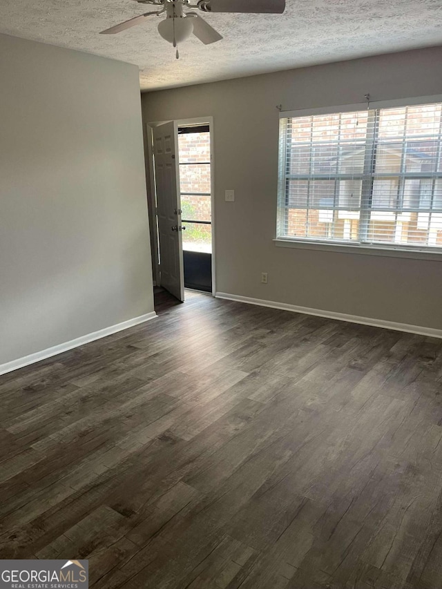 empty room featuring ceiling fan, dark wood-type flooring, and a textured ceiling