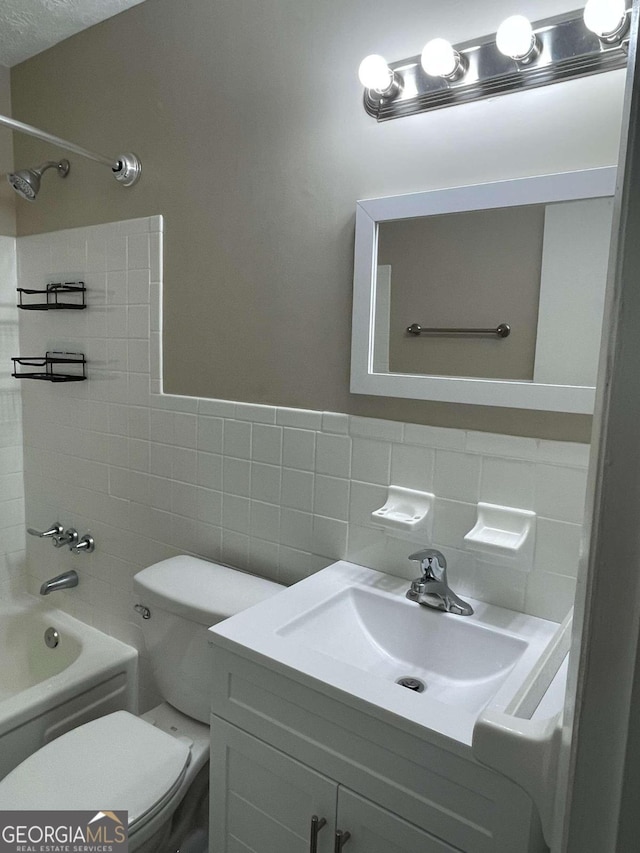 full bathroom featuring tiled shower / bath combo, vanity, tile walls, and toilet