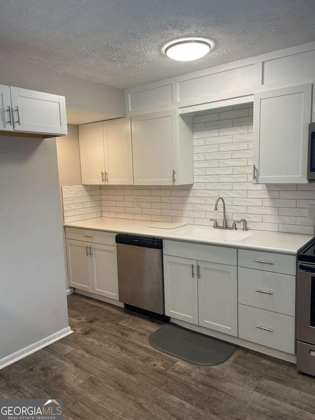 kitchen featuring appliances with stainless steel finishes, tasteful backsplash, sink, white cabinets, and dark hardwood / wood-style flooring