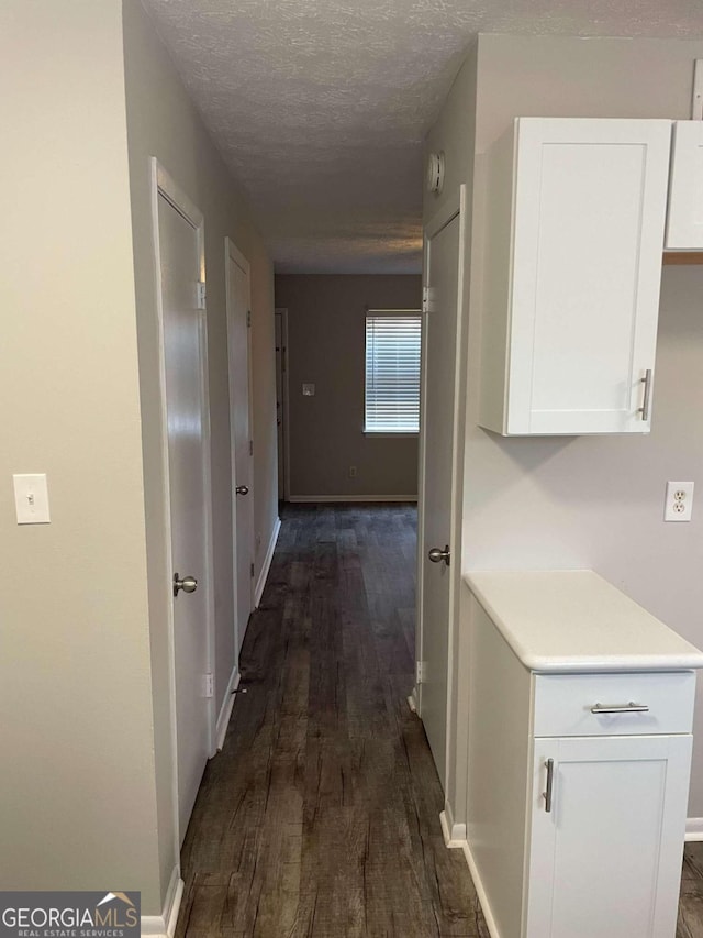 corridor with dark hardwood / wood-style flooring and a textured ceiling