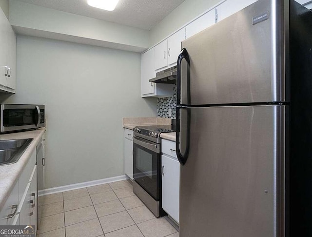 kitchen with white cabinets, decorative backsplash, light tile patterned floors, a textured ceiling, and appliances with stainless steel finishes