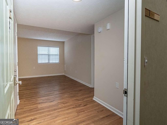 empty room with a textured ceiling and light wood-type flooring