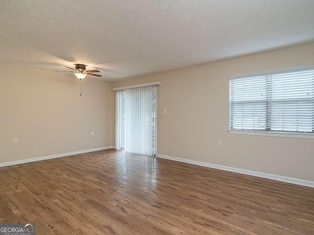 empty room featuring ceiling fan, dark wood-type flooring, and a textured ceiling