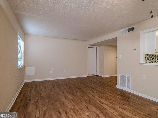 spare room featuring a textured ceiling and dark wood-type flooring