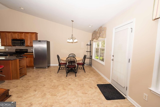 kitchen with vaulted ceiling, pendant lighting, stainless steel fridge, a chandelier, and electric stove