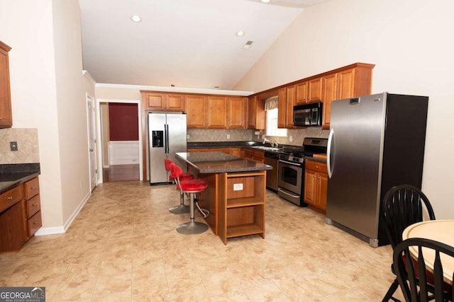 kitchen with lofted ceiling, a kitchen bar, dark stone counters, a center island, and stainless steel appliances