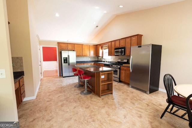 kitchen featuring a breakfast bar, high vaulted ceiling, decorative backsplash, a center island, and stainless steel appliances