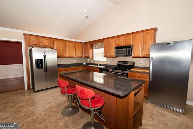 kitchen featuring stainless steel appliances, a kitchen bar, a kitchen island, and backsplash