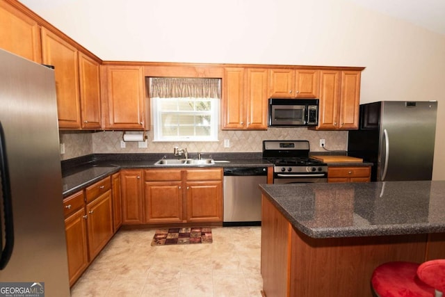 kitchen featuring lofted ceiling, sink, appliances with stainless steel finishes, a kitchen breakfast bar, and tasteful backsplash