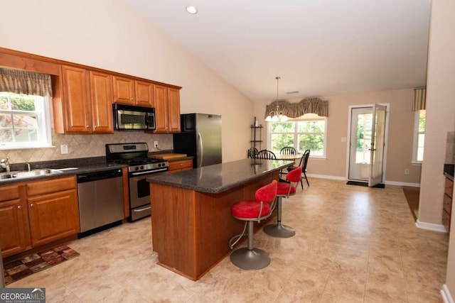 kitchen with sink, a breakfast bar, appliances with stainless steel finishes, a kitchen island, and decorative backsplash