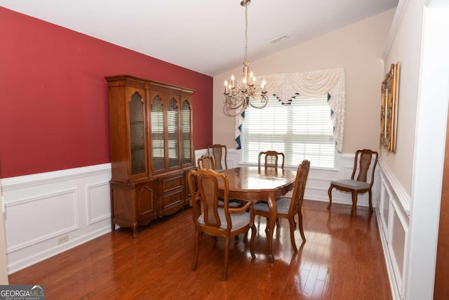 dining space featuring an inviting chandelier, lofted ceiling, and dark hardwood / wood-style floors