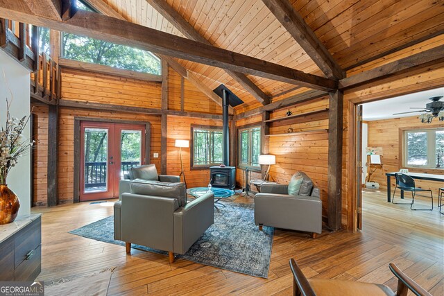 living room featuring beam ceiling, a wood stove, high vaulted ceiling, wood ceiling, and ceiling fan