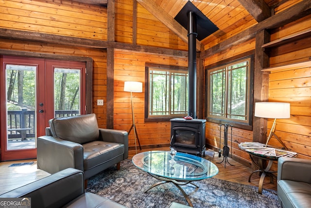 living room with wood-type flooring, wood walls, a healthy amount of sunlight, and a wood stove