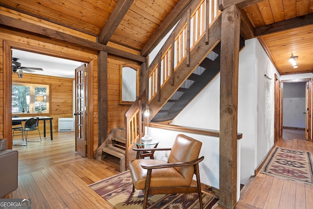 staircase featuring wood walls, hardwood / wood-style flooring, wooden ceiling, and ceiling fan