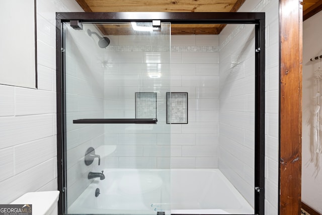 bathroom featuring toilet and bath / shower combo with glass door