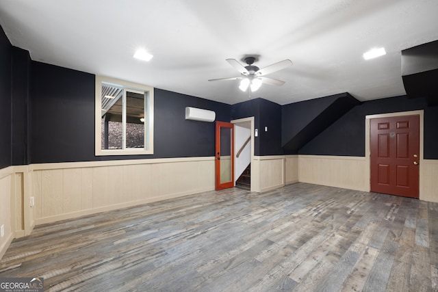 bonus room with hardwood / wood-style floors, a wall mounted air conditioner, and ceiling fan