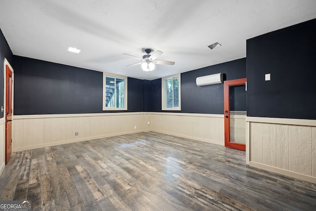 empty room with ceiling fan, dark wood-type flooring, and a wall mounted air conditioner