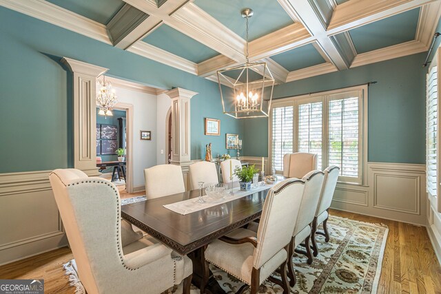 dining space with an inviting chandelier, light wood-type flooring, ornate columns, coffered ceiling, and beam ceiling