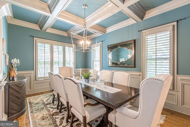 dining space featuring a healthy amount of sunlight, coffered ceiling, and light hardwood / wood-style floors