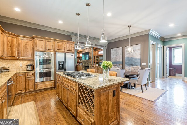 kitchen with a center island, stainless steel appliances, light stone countertops, and light hardwood / wood-style floors