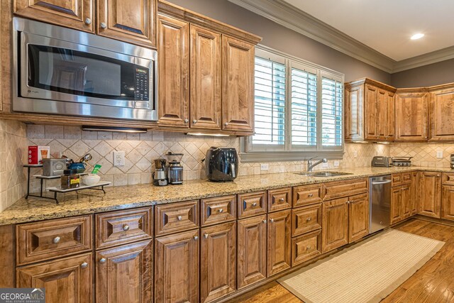 kitchen with crown molding, light hardwood / wood-style flooring, sink, and appliances with stainless steel finishes