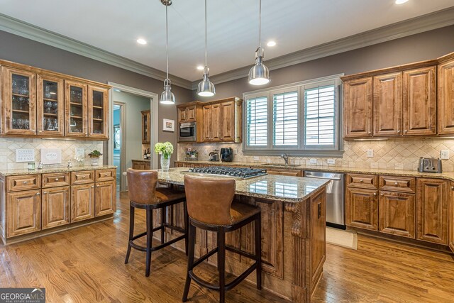 kitchen featuring a kitchen island, light stone countertops, appliances with stainless steel finishes, and light hardwood / wood-style floors