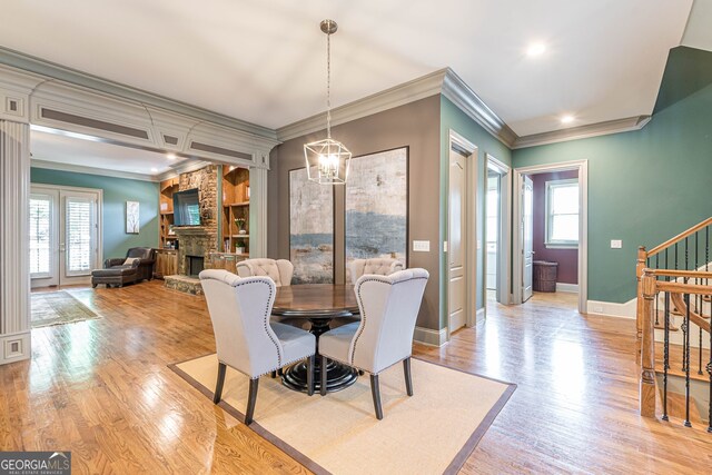 dining space featuring a wealth of natural light, crown molding, light wood-type flooring, and a fireplace