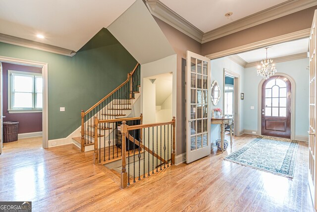 entrance foyer featuring ornamental molding, a notable chandelier, and light hardwood / wood-style floors