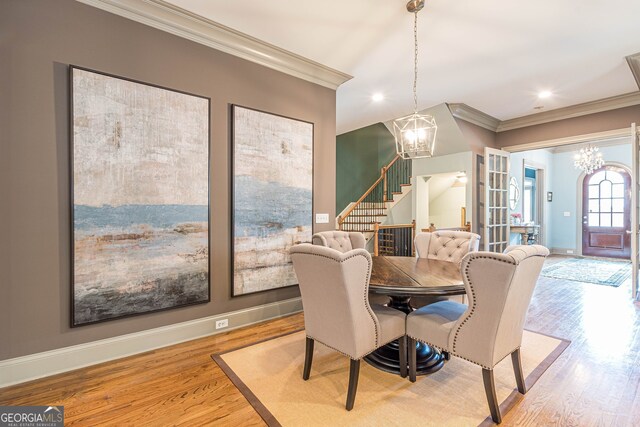 dining space featuring ornamental molding, light hardwood / wood-style flooring, and a notable chandelier