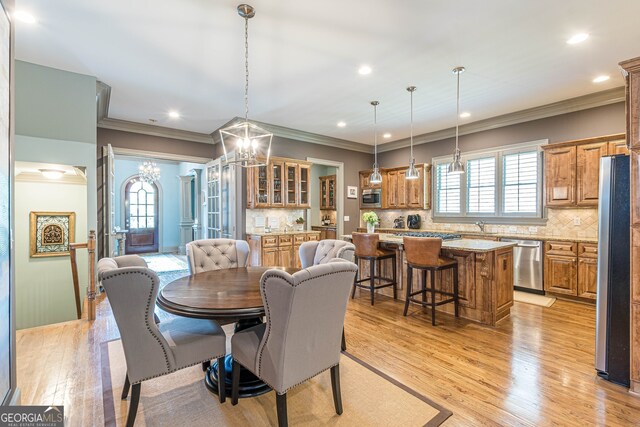 dining room featuring a chandelier, light hardwood / wood-style floors, and crown molding