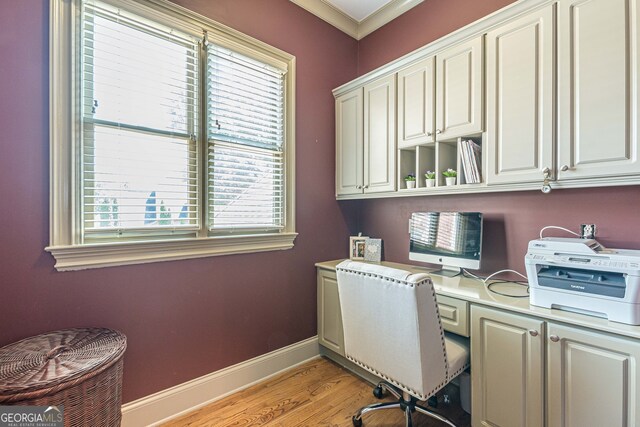 home office featuring light hardwood / wood-style flooring, ornamental molding, and built in desk