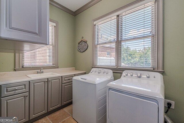 laundry area with ornamental molding, cabinets, sink, and washer and clothes dryer