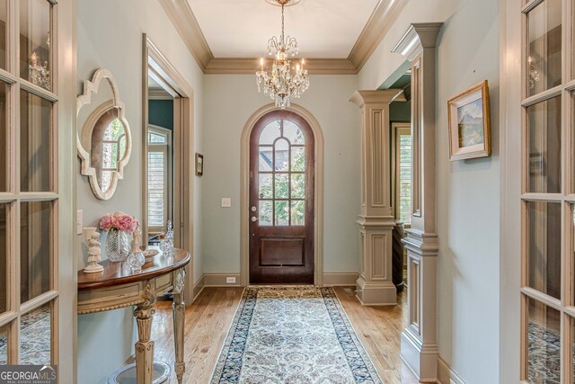 foyer entrance with crown molding, plenty of natural light, a notable chandelier, and light hardwood / wood-style floors