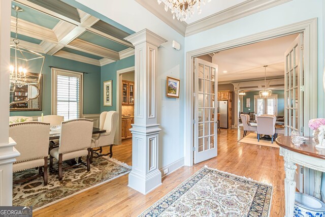 dining area with decorative columns, light hardwood / wood-style floors, and a notable chandelier